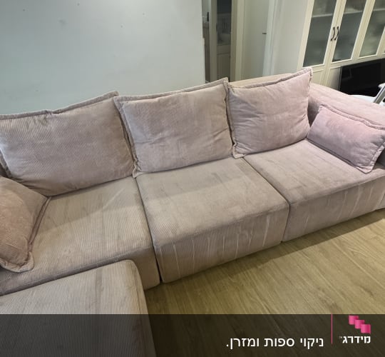 ספה בהירה בחדר מגורים עם רצפת עץ